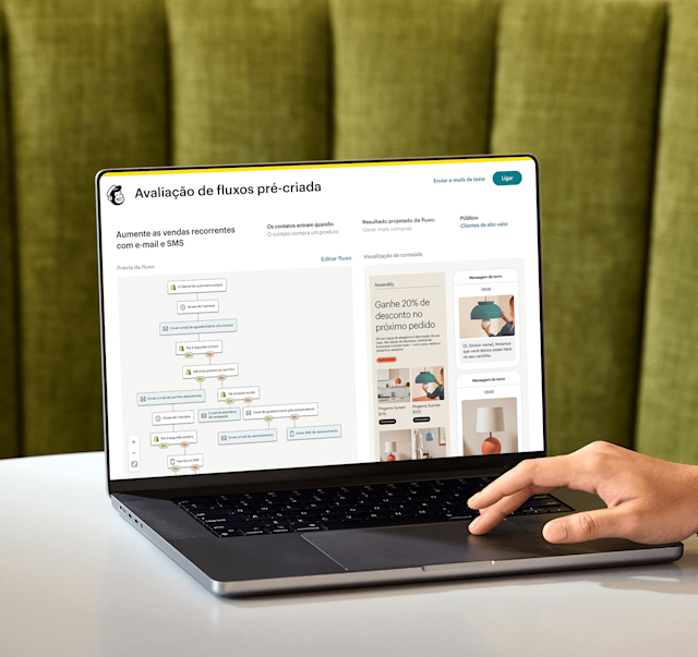 Imagem de uma pessoa sentada à mesa, olhando para a tela de um notebook que exibe o recurso de análise de jornada pronta para uso do Mailchimp. O recurso mostra uma prévia de uma jornada de automação e uma visão abstrata das interfaces de e-mail e SMS da marca fictícia Assembly. 