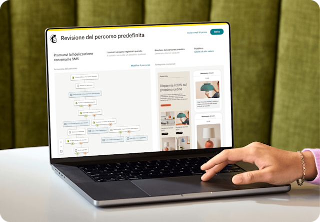 Immagine di una persona seduta a una scrivania, che guarda lo schermo di un laptop che mostra la funzionalità di revisione del percorso predefinito di Mailchimp. La funzionalità mostra l'anteprima di un percorso di automazione e una visualizzazione astratta delle interfacce e-mail e SMS del brand fittizio Assembly. 